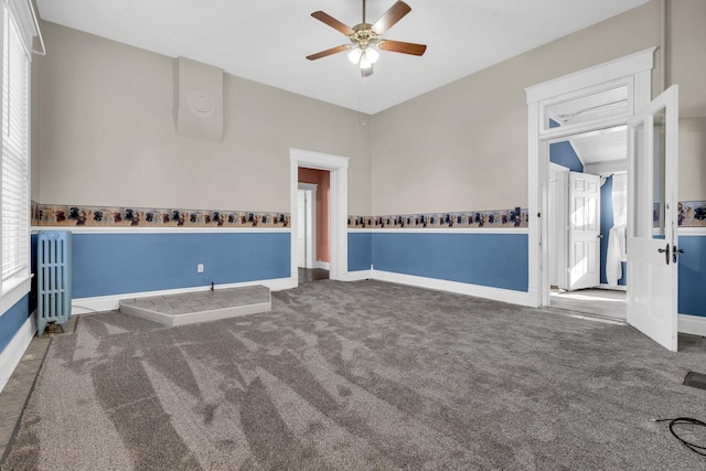 carpeted empty room with radiator heating unit, ceiling fan, and vaulted ceiling