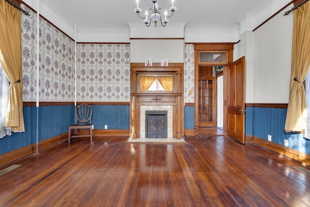 unfurnished living room with an inviting chandelier, dark hardwood / wood-style flooring, and ornamental molding