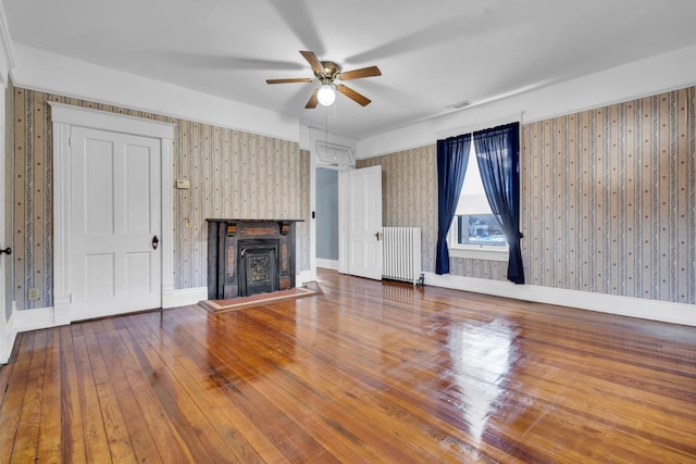 unfurnished living room with hardwood / wood-style flooring, ceiling fan, and radiator