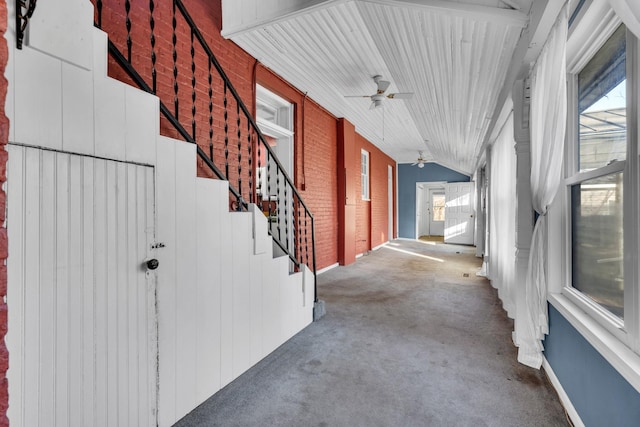 hallway with lofted ceiling, brick wall, and carpet flooring