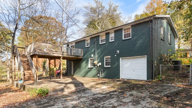 rear view of property featuring a wooden deck and a garage