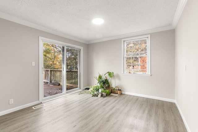 empty room featuring ornamental molding, light hardwood / wood-style floors, and a textured ceiling