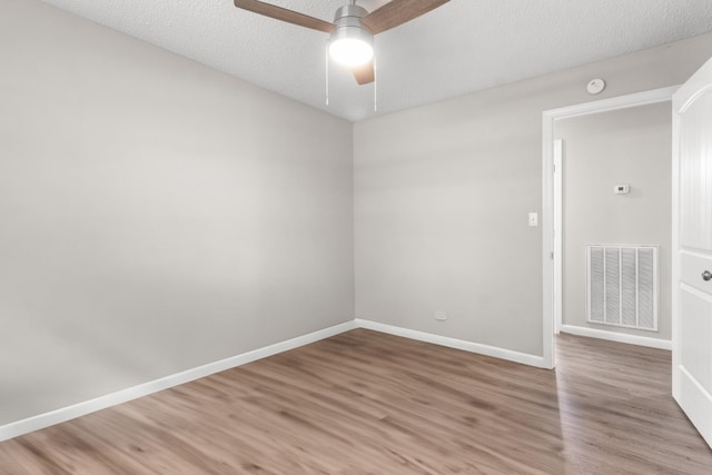 empty room with ceiling fan, wood-type flooring, and a textured ceiling