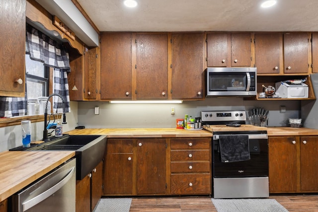 kitchen featuring wood counters, sink, light wood-type flooring, and appliances with stainless steel finishes