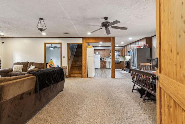 carpeted living room featuring ceiling fan, crown molding, and a textured ceiling