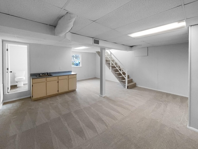 basement with sink, light carpet, and a drop ceiling