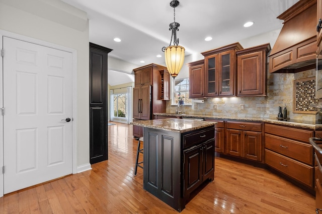 kitchen featuring a breakfast bar, a center island, light hardwood / wood-style flooring, black electric cooktop, and decorative backsplash