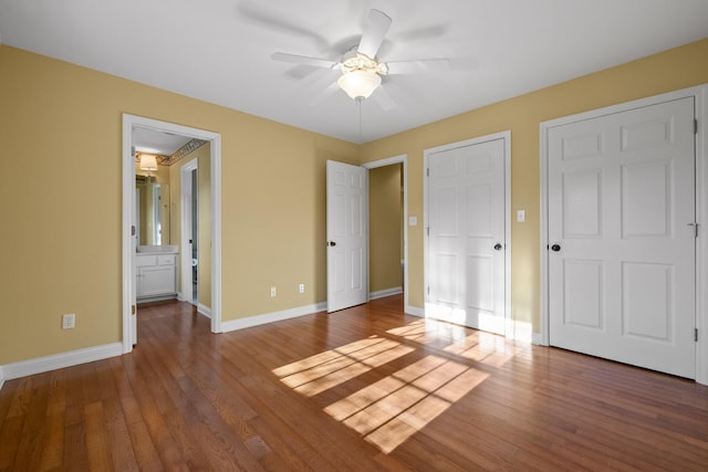 unfurnished bedroom featuring ceiling fan, ensuite bathroom, and hardwood / wood-style floors