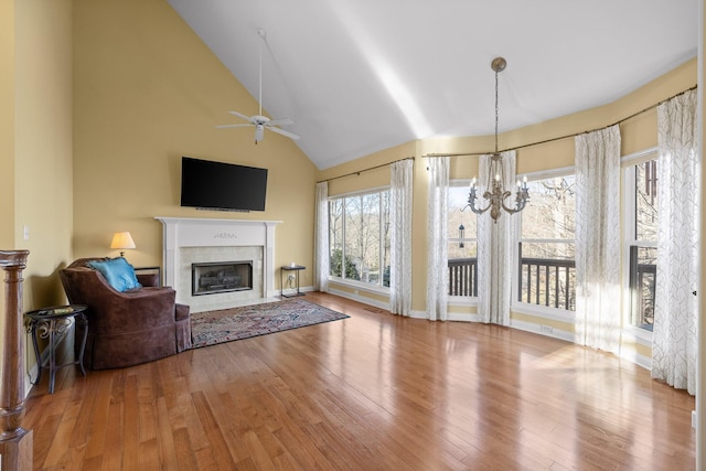 living room with ceiling fan with notable chandelier, hardwood / wood-style floors, and high vaulted ceiling