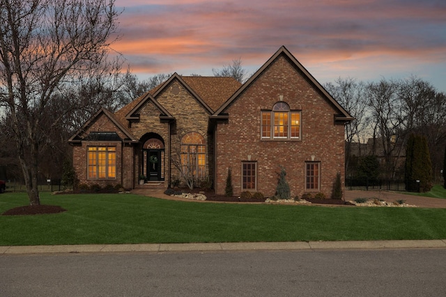 view of front facade featuring stone siding, brick siding, and a lawn