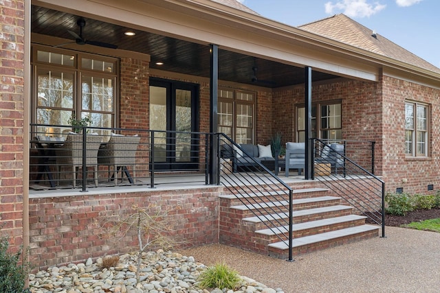 view of exterior entry featuring brick siding, crawl space, and a shingled roof