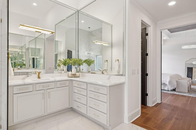 ensuite bathroom featuring crown molding, double vanity, recessed lighting, a sink, and ensuite bath