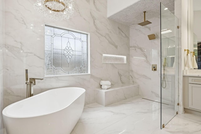 bathroom featuring marble finish floor, a marble finish shower, a freestanding bath, vanity, and stone wall