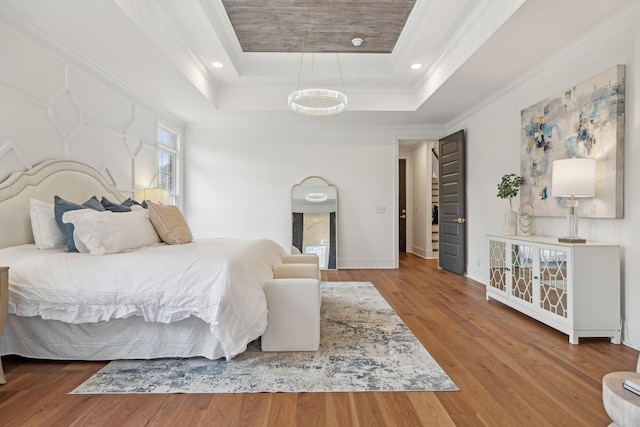 bedroom featuring crown molding, a tray ceiling, wood finished floors, and recessed lighting