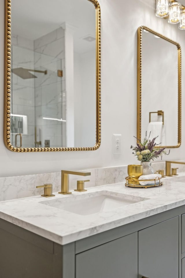 full bath with a marble finish shower and vanity