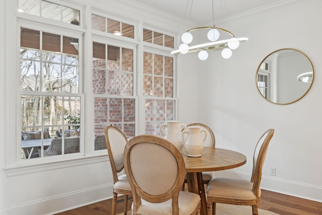 dining space with a notable chandelier, ornamental molding, dark wood-style flooring, and baseboards