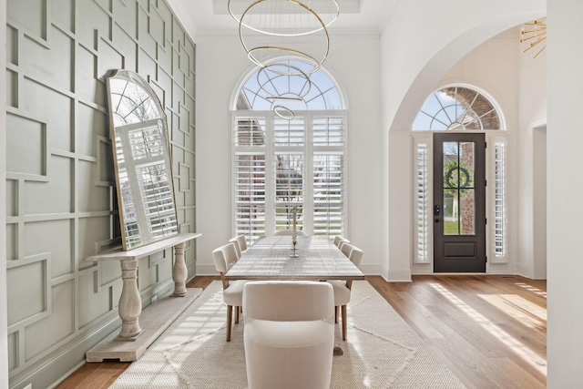 entrance foyer with a chandelier, light wood finished floors, a high ceiling, and crown molding