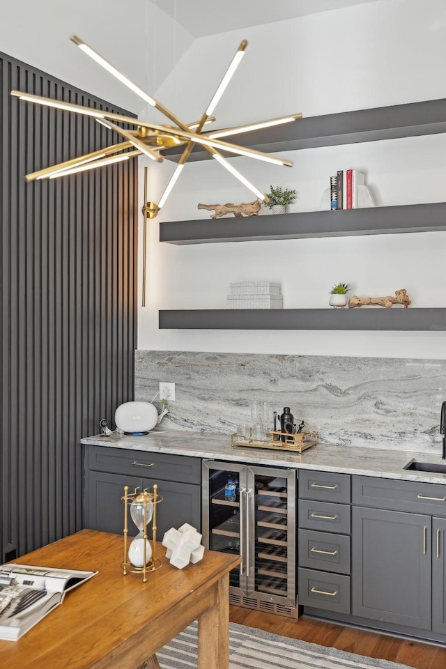 bar featuring beverage cooler, decorative backsplash, dark wood-type flooring, bar area, and a sink