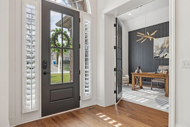 foyer with a chandelier, wood finished floors, visible vents, and a healthy amount of sunlight