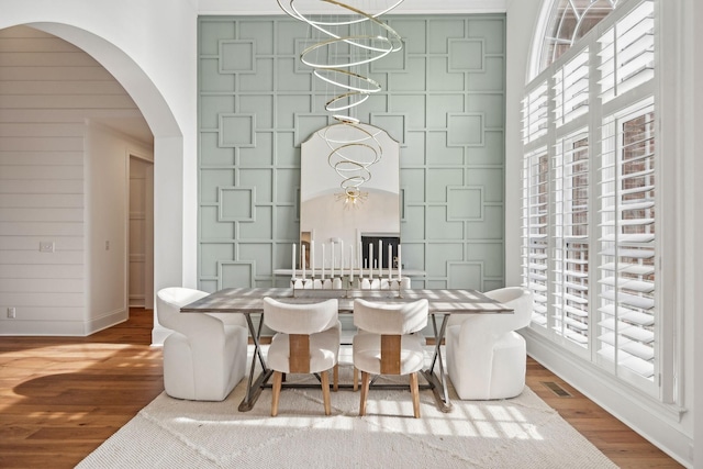 dining space featuring a wealth of natural light, arched walkways, and wood finished floors