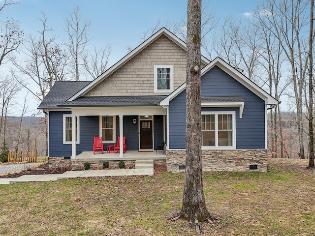 view of front of house featuring covered porch, stone siding, a shingled roof, and crawl space