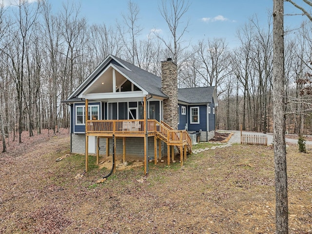 view of front of house with a sunroom, a chimney, and stairs