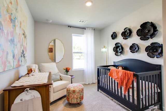 bedroom featuring a nursery area and light colored carpet