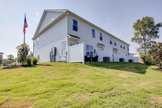 back of house featuring central air condition unit and a lawn