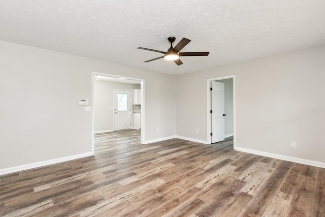 empty room featuring dark wood-type flooring, ceiling fan, and a textured ceiling