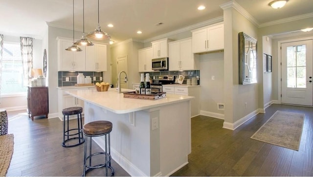 kitchen featuring white cabinetry, an island with sink, appliances with stainless steel finishes, and hanging light fixtures