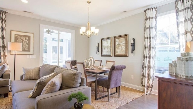 dining area with ornamental molding, a healthy amount of sunlight, hardwood / wood-style floors, and a notable chandelier