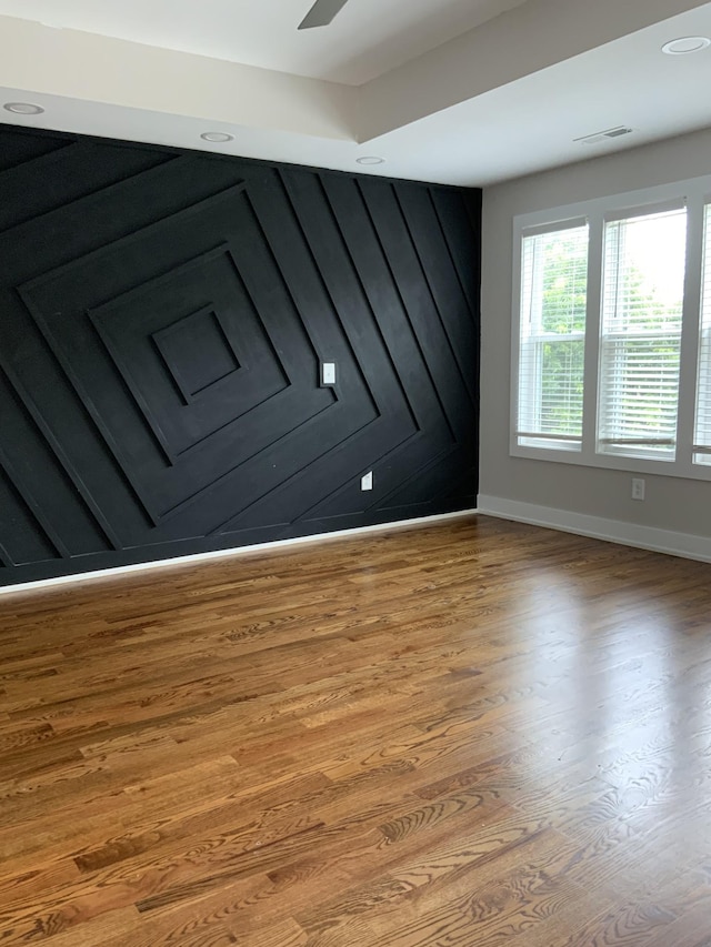 spare room with ceiling fan, a wood stove, and light hardwood / wood-style floors