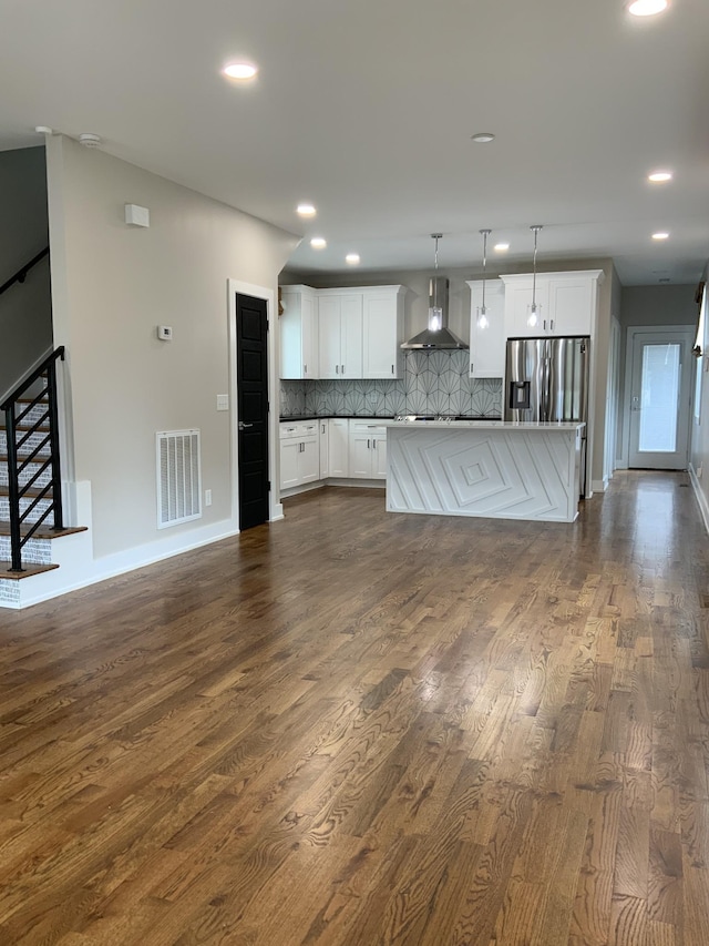 kitchen featuring wall chimney exhaust hood, stainless steel fridge with ice dispenser, pendant lighting, decorative backsplash, and white cabinets