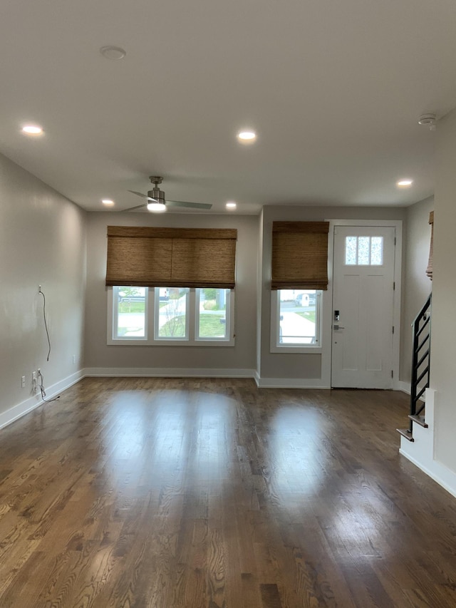 unfurnished living room featuring ceiling fan, a healthy amount of sunlight, and dark hardwood / wood-style floors