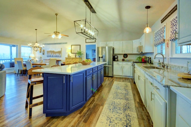 kitchen featuring appliances with stainless steel finishes, pendant lighting, white cabinetry, sink, and a kitchen breakfast bar