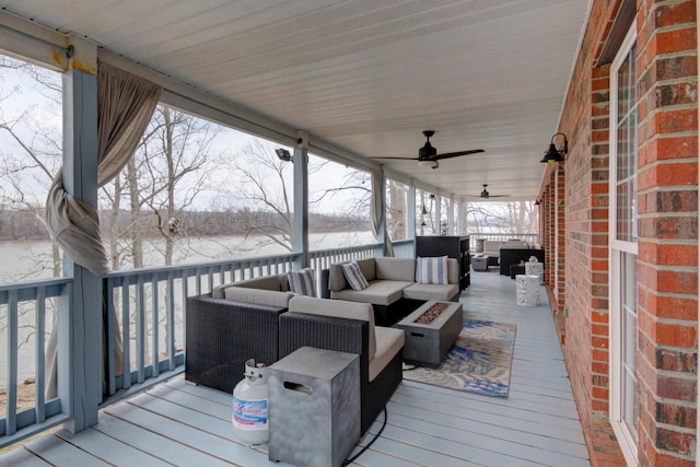 snow covered deck with an outdoor living space with a fire pit and ceiling fan