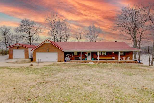 ranch-style house featuring a garage, a lawn, and a porch