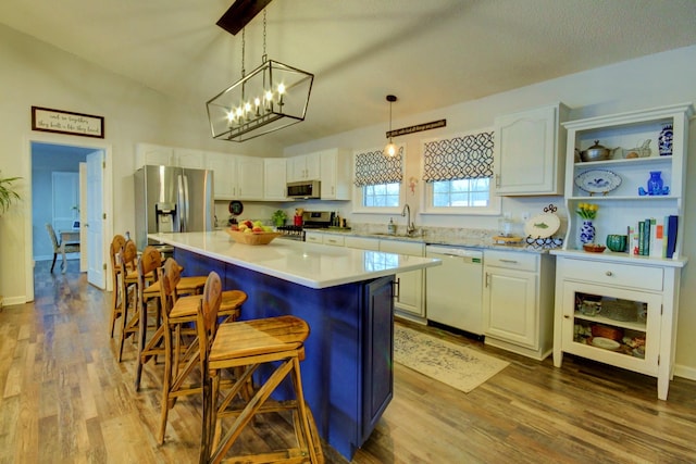 kitchen with a breakfast bar area, white cabinetry, a center island, pendant lighting, and stainless steel appliances