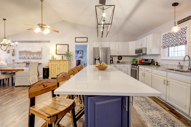 kitchen with pendant lighting, appliances with stainless steel finishes, sink, and white cabinets