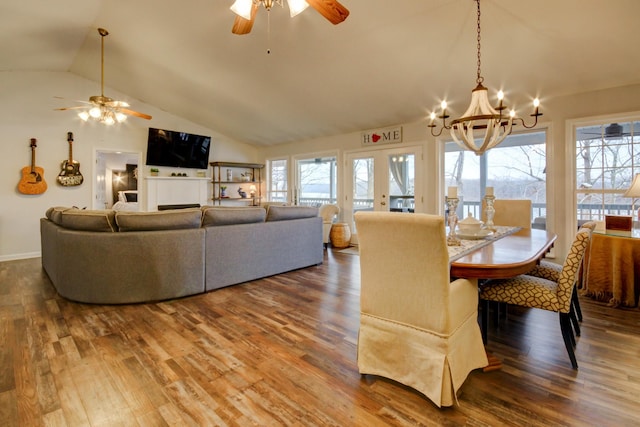 dining room with ceiling fan with notable chandelier, wood-type flooring, and vaulted ceiling