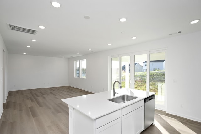 kitchen featuring sink, white cabinetry, light wood-type flooring, dishwasher, and an island with sink