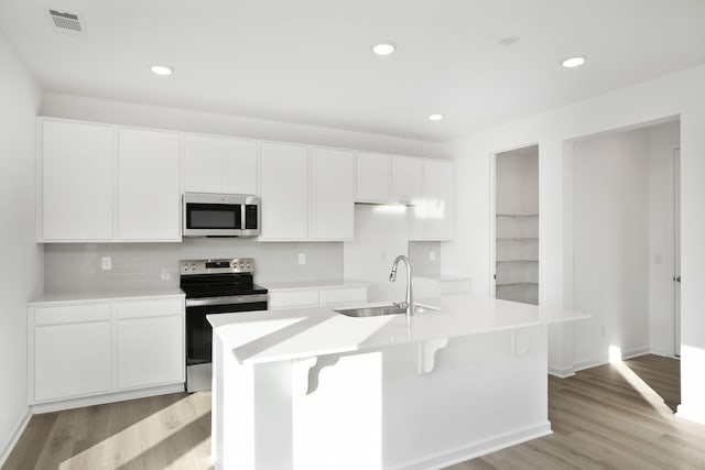 kitchen with sink, light hardwood / wood-style flooring, a kitchen island with sink, white cabinetry, and stainless steel appliances