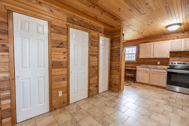 kitchen with light brown cabinets, stainless steel range with electric cooktop, and wooden walls