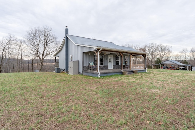 back of property with cooling unit, a lawn, and covered porch