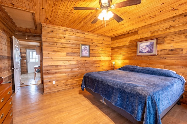 bedroom featuring ceiling fan, wooden walls, light hardwood / wood-style floors, and wooden ceiling