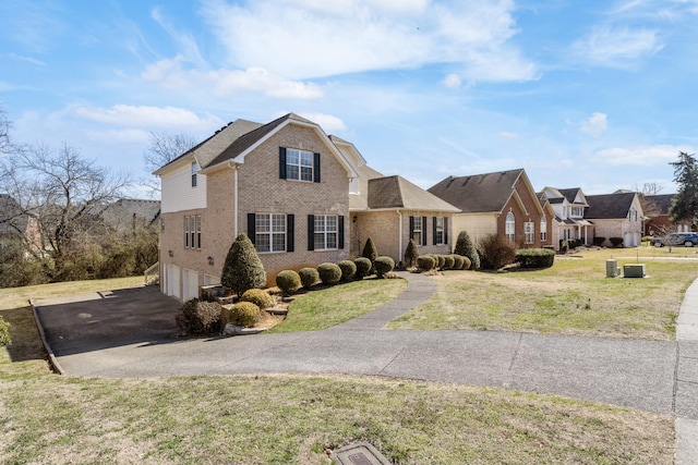 traditional-style home with an attached garage, driveway, a front yard, and brick siding