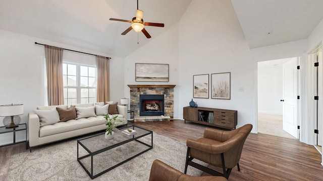 living room with hardwood / wood-style flooring, a stone fireplace, and high vaulted ceiling