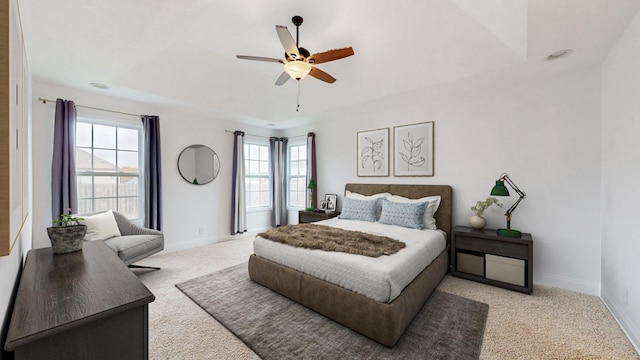 bedroom featuring light carpet, ceiling fan, and a tray ceiling