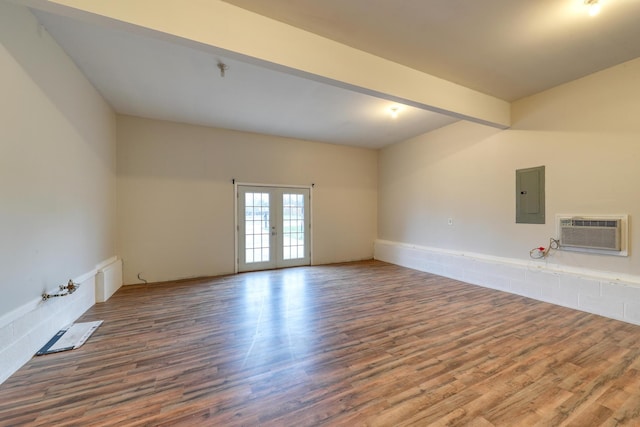 empty room with french doors, electric panel, a wall mounted AC, and hardwood / wood-style flooring