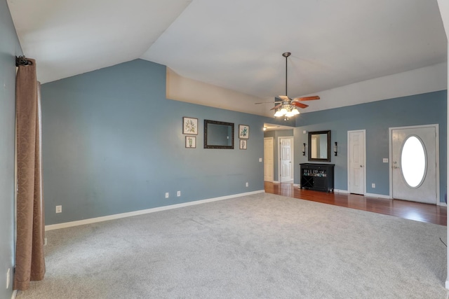 unfurnished living room with dark colored carpet, vaulted ceiling, and ceiling fan